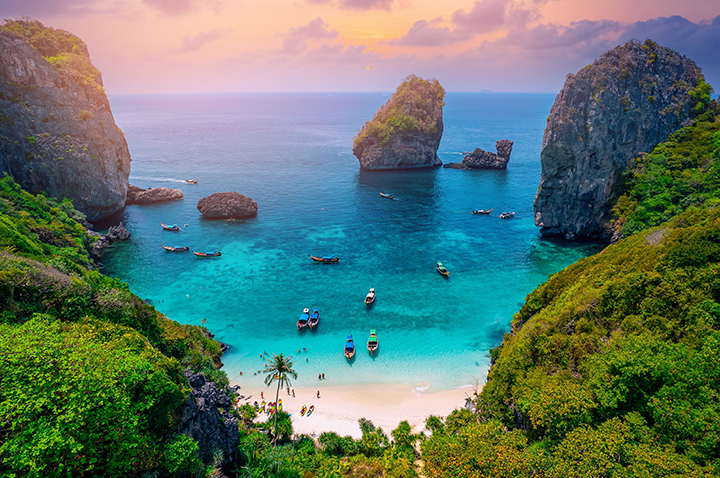Malerischer Strand von Koh Phi Phi, Thailand, umgeben von grünen Klippen und strahlend blauem Wasser