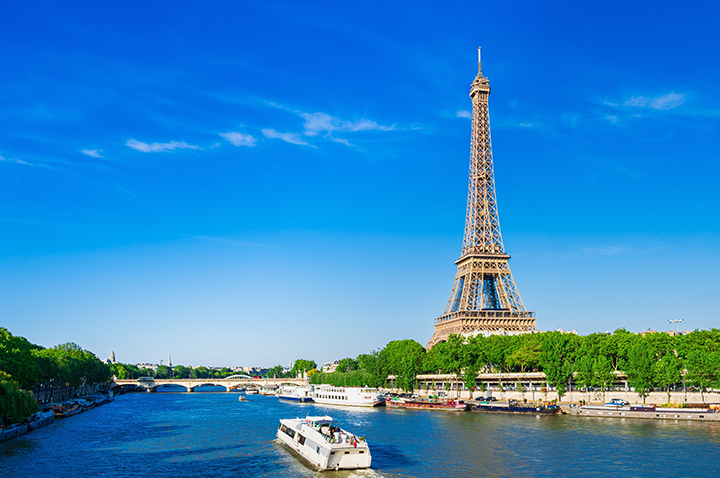 Ein Boot gleitet auf einem Fluss in Paris, während ein hoher Turm im Hintergrund aufragt.