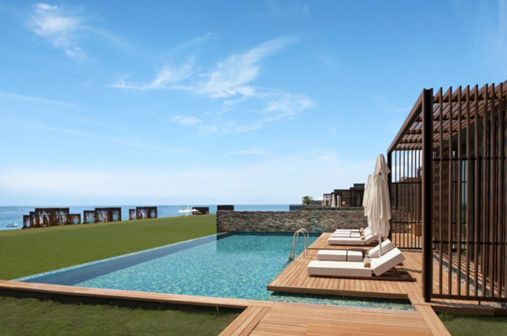 Infinity-Pool mit Liegestühlen und Sonnenschirmen auf Holzdeck neben Meerblick. Infinity-Pool mit Liegestühlen und Sonnenschirmen auf Holzdeck neben Meerblick.