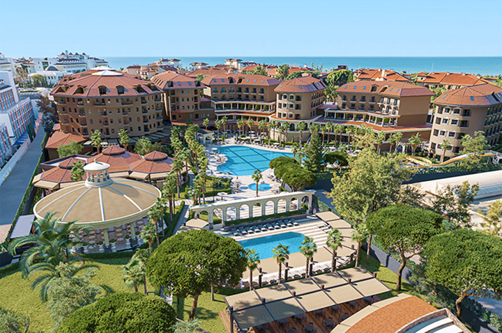 Hotelanlage mit mehreren Gebäuden in mediterranem Stil, großen Pools und umgeben von Bäumen und Palmen unter blauem Himmel.