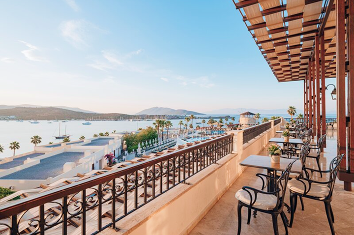 Hotelbalkon mit Aussicht auf das strahlende Meer und sanfte Wellen im Hintergrund.