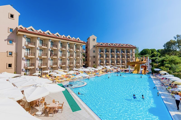 Blick auf einen großen Pool und Sonnenliegen vor einem Hotel, ideal für Entspannung und Sonne.