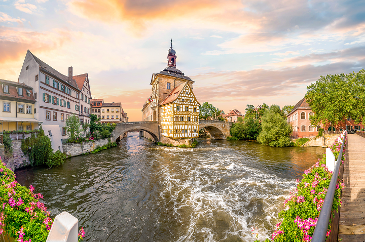 Ein Fluss fließt durch eine Stadt, mit einem Brücke und mehreren Gebäuden im Hintergrund.