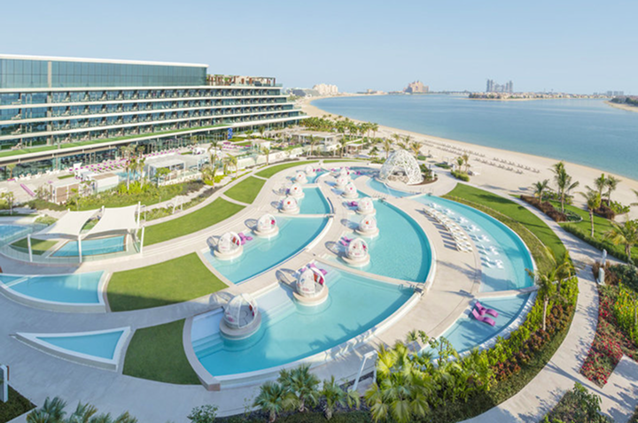 Strandclub des Hotels in Dubai mit Liegen, Palmen und Blick auf das glitzernde Wasser des Persischen Golfs.