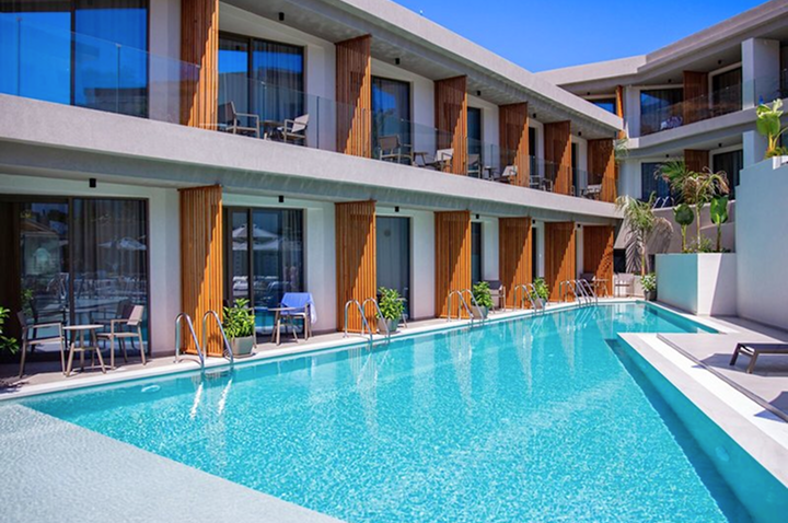 Moderner Hotelkomplex mit rechteckigem Pool und Holzverkleidungen an den Balkonen.