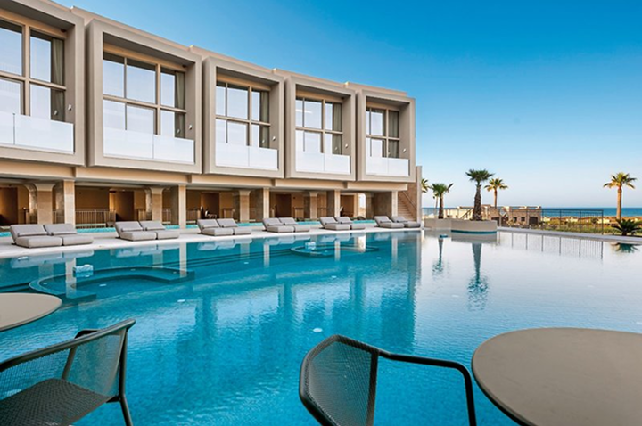 Der Pool im Luxushotel am Strand bietet eine entspannende Atmosphäre, umgeben von komfortablen Liegen für Gäste.