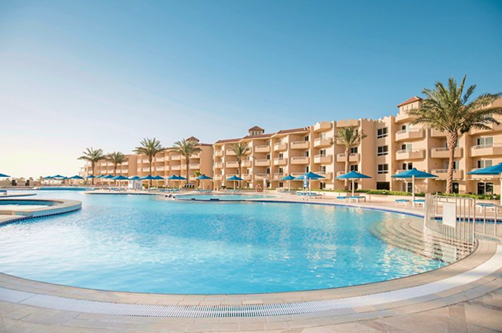 Blick auf den einladenden Pool des Strandclubs, umgeben von Sonnenliegen und tropischen Pflanzen.