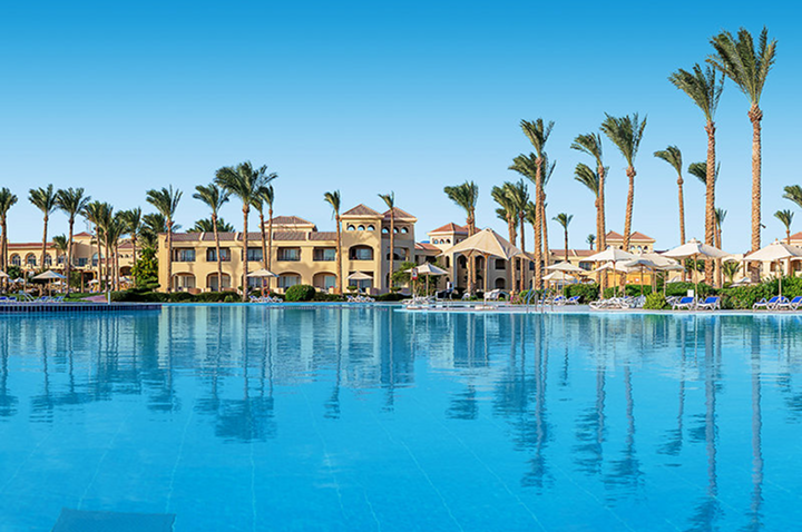 Entspannender Poolbereich mit Liegen und Schirmen vor einem Hotel, perfekt für einen sonnigen Tag am Wasser.