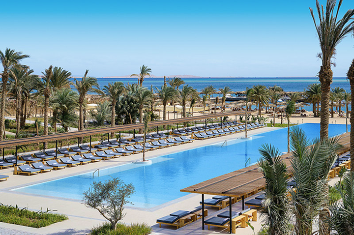 Großer rechteckiger Pool mit Liegen und Palmen in einer Strandhotelanlage am Meer. Großer rechteckiger Pool mit Liegen und Palmen in einer Strandhotelanlage am Meer.