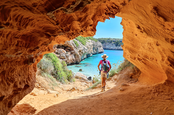 Eine Person geht durch eine Höhle am Strand von Mallorca.