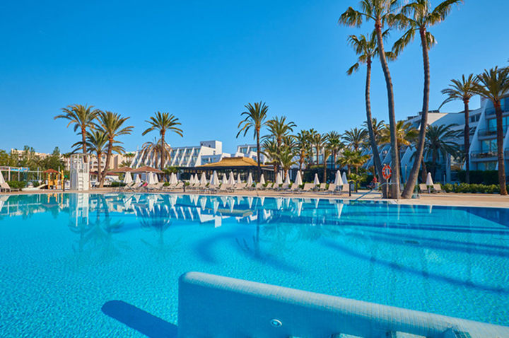 Ein großer Swimmingpool umgeben von Liegen und Palmen, ideal für Entspannung und Erholung an einem sonnigen Tag.