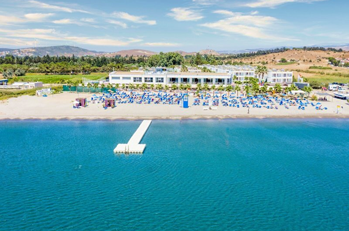 Luftaufnahme eines Strandes mit einem Hotel, das direkt am Wasser liegt, umgeben von Palmen und Sonnenliegen. Luftaufnahme eines Strandes mit einem Hotel, das direkt am Wasser liegt, umgeben von Palmen und Sonnenliegen.