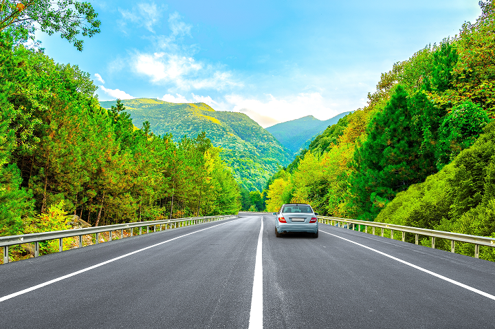 Ein Auto bewegt sich auf einer Straße, die durch einen malerischen Wald in Deutschland führt. Ein Auto bewegt sich auf einer Straße, die durch einen malerischen Wald in Deutschland führt.