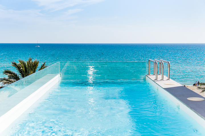 Ein Pool mit Blick auf den Ozean unter klarem, blauem Himmel – der perfekte Ort für einen Luxusurlaub. Ein Pool mit Blick auf den Ozean unter klarem, blauem Himmel – der perfekte Ort für einen Luxusurlaub.