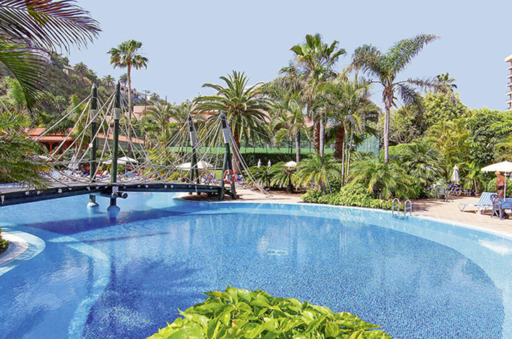 Ein großer Pool, umgeben von Palmen und einem Hotelgebäude, strahlt Urlaubsstimmung und Entspannung aus. Ein großer Pool, umgeben von Palmen und einem Hotelgebäude, strahlt Urlaubsstimmung und Entspannung aus.